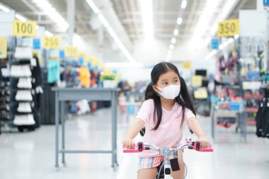 Asyalı çocuk ya da çocuk spor mağazasındaki spor mağazalarında bisiklet sürerken ya da bisiklet sürerken maske takıyor. Tatillerde sağlıklı egzersiz yapmak için Coronavirüs 'ü ya da toz bulutunu korumak adına dinleniyor.