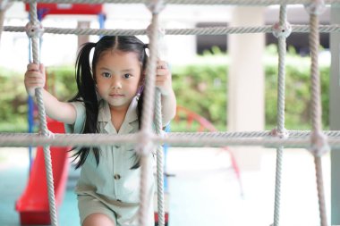 Asyalı şirin çocuk ya da gülümseyen çocuk halat tırmanışı ve mutlu eğlence ya da neşe tatilin tadını çıkarın. Çocuk klübünde, anaokulunda, çocuk parkında ve anaokulunda egzersiz yapın.