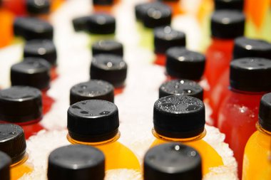 Buzlu meyve ya da sebze suyu plastik şişede buz gibi soğuk ve turuncu yeşil kırmızı ya da renkli kivi suyu ya da elma çileği ve havuç vitamin içeceği ve sağlık ya da tatlı içecek için.