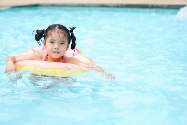 アジアの子供のかわいいまたは子供の女の子は スイミングプールやウォーターパークで楽しい笑顔で泳ぐことができないので ライフリングを身に着けている夏休みのホテルリゾート旅行での運動で新鮮なリラックス — ストック写真