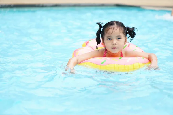 アジアの子供がかわいいまたは子供の女の子が水泳プールやウォーターパークで泳ぐことができず ホテルリゾートの夏休み旅行で運動でリラックスして楽しむことができないので 水泳ライフリングを着用 — ストック写真