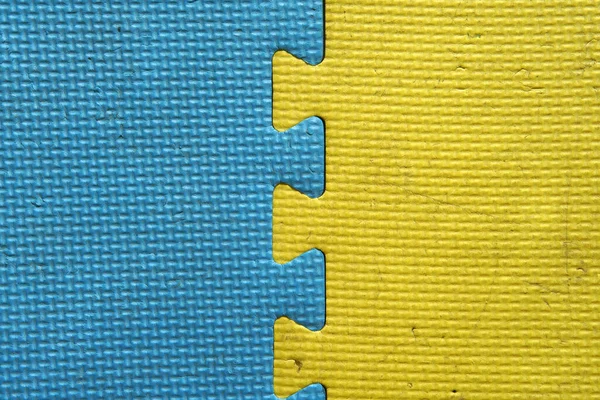 old and dirty yellow and blue foam or rubber floor and colorful soft board on top view for baby children protect and play on playground or kid playroom and for texture or background with wallpaper