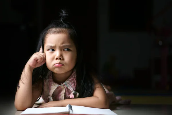 アジアの子供の緊張や子供の女の子の学生の睡眠読書や宿題や日記や幼稚園教室や保育園で床の上の本や黒のスペースを持つ家庭での新しいアイデアを考えます — ストック写真