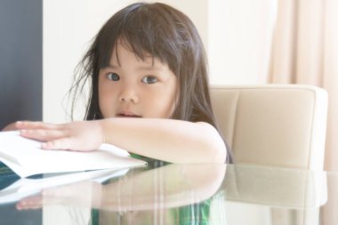 Asyalı çocuklar şirin ya da kız çocuğu gülümsemesi ya da öğrenci eğitimi için kitap okumaktan zevk alır. Cam masaya ve çocuk yuvasında ya da anaokulunda ya da yumuşak anaokulunda sandalyeye otururlar.