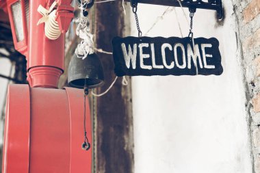 Eski moda ve eski moda bir hoş geldin tabelası. Üzerinde çan, kutsal iplik, kırmızı kutu ve lamba var. Bar veya restoranda ve şehir sokaklarında terk edilmiş.