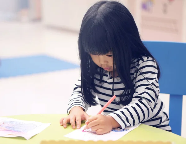 アジアの子供かわいいまたは子供の女の子は 柔らかい焦点とヴィンテージブルーに保育園やプリスクールで椅子と白い紙とカラフルなテーブルの上に着色や手描きのペイントのための学習に集中 — ストック写真