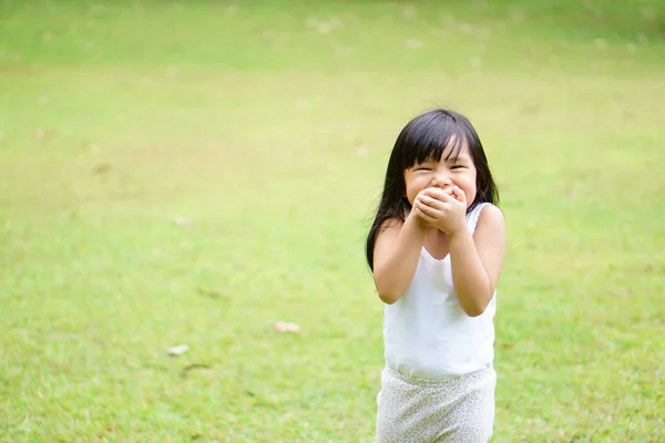 アジアの子供たちかわいいまたは子供の女の子陽気なスタンド笑顔笑いと手を閉じて口の中で幸せな楽しみのために楽しむか 白いベストを着て緑の芝生の牧草地のスペースでギャグと秘密 — ストック写真