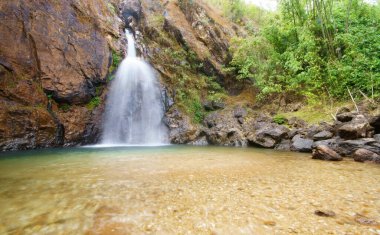 Görülmemiş yeşil zümrüt suyu ve dinlenmek için kayaları olan ve doğa manzarası için Jokkradin şelalesi veya ormandaki ağaç ve çakıl ile serinletici serinleyen bir şelale.