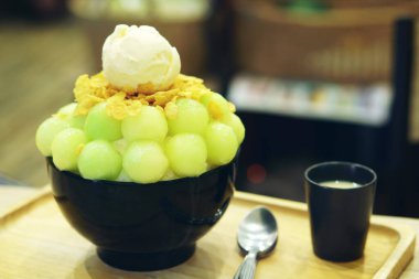 Vanilyalı dondurma ve tahıllı mısır gevreği içinde yeşil kavun Bingsu, ahşap tabakta tatlandırılmış süt ve cafe restoranındaki masada da tatlı tatlı olarak beyaz şarap.