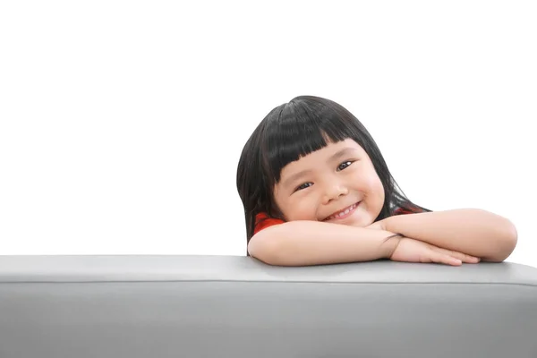 アジアの子供たちかわいいまたは子供の女の子幸せな楽しみと笑顔で赤いシャツでソファの上に就学前や保育園で宇宙と隔離された白の上に — ストック写真