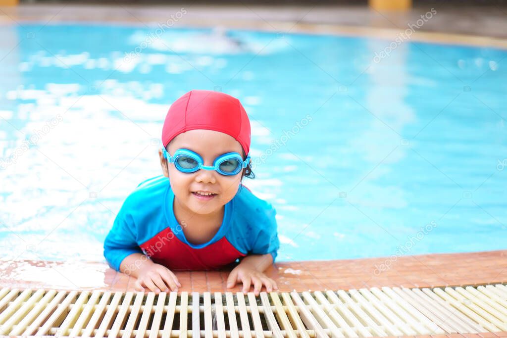 Niña asiática con manzana en la piscina con gafas de natación de desgaste