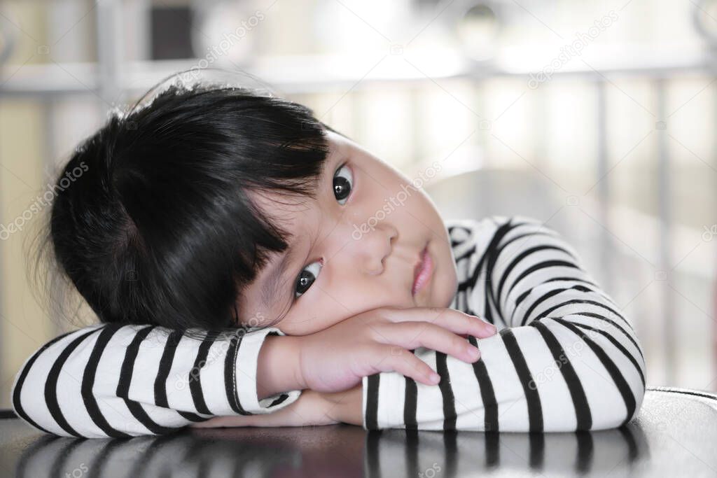 Asian children cute or kid girl sleep and open eye for relax on table at nursery or kindergarten
