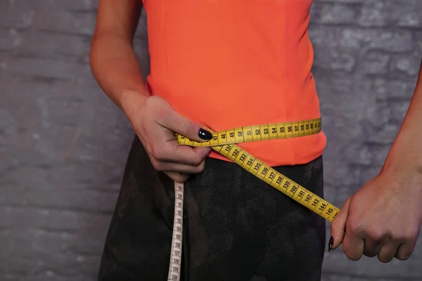 girl uses a measuring cup to measure the body's circumference