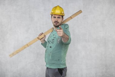 inşaat işçisi elinde bir tahta parçası tutar,