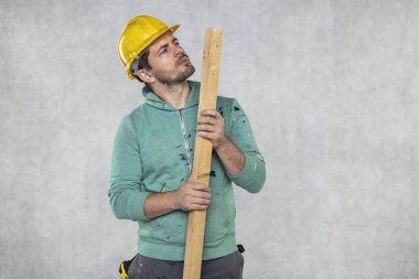 inşaat işçisi elinde bir tahta parçası tutar,