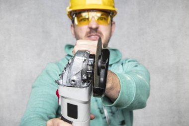 inşaat işçisi elinde bir açı değirmeni tutar