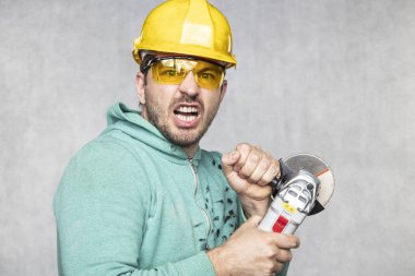 inşaat işçisi elinde bir açı değirmeni tutar