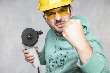 inşaat işçisi elinde bir açı değirmeni tutar