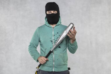 Maskeli bir holigan elinde bir beyzbol sopası tutar