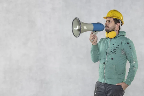 Der Bauarbeiter hält ein Megafon in der Hand, die — Stockfoto