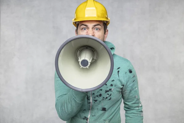 Der Bauarbeiter hält ein Megafon in der Hand, die — Stockfoto