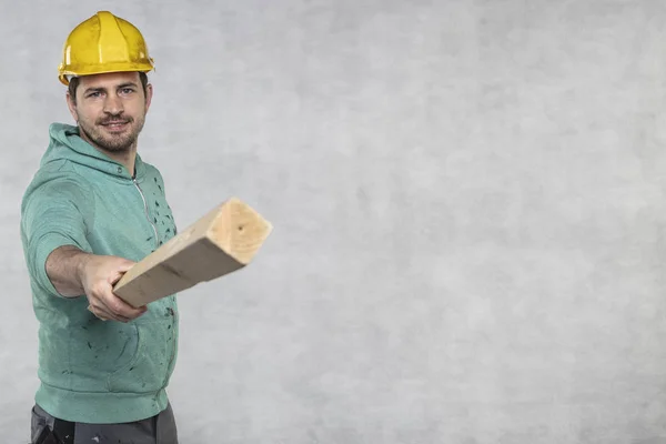 Stavební pracovník drží v rukou kus desky, — Stock fotografie