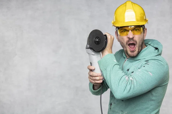 De bouwvakker houdt een Haakse slijper in zijn hand — Stockfoto