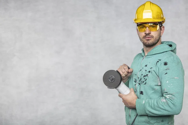 Byggnadsarbetaren håller en vinkelslip i handen — Stockfoto
