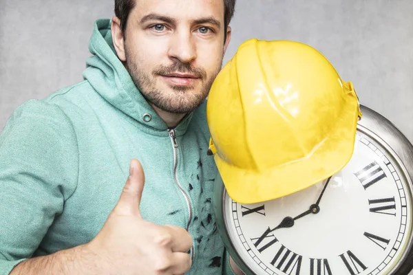 O construtor está segurando o relógio em suas mãos — Fotografia de Stock