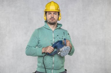 inşaat işçisi elinde yeni bir öğütücü tutar