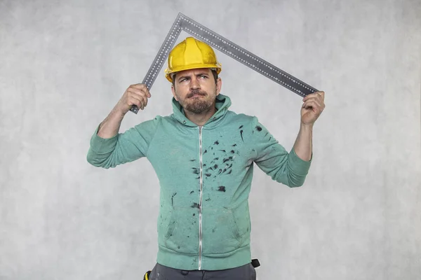 De bouwvakker houdt een hoek in de hand, een gids — Stockfoto