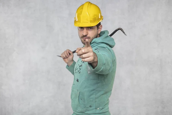 De bouwvakker houdt een werktuig in zijn handen, een crowba — Stockfoto