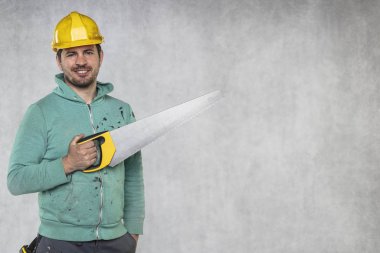 inşaat yapıcı elinde bir testere ile duruyor, kopya