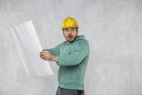 Překvapený stavební pracovník reviduje stavební plány — Stock fotografie
