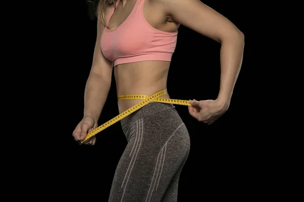 Mladá žena s atletickou karoserii používá měřicí pásku — Stock fotografie