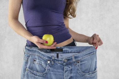 genç atletik kadın siluet, elma ve eski büyük pantolon