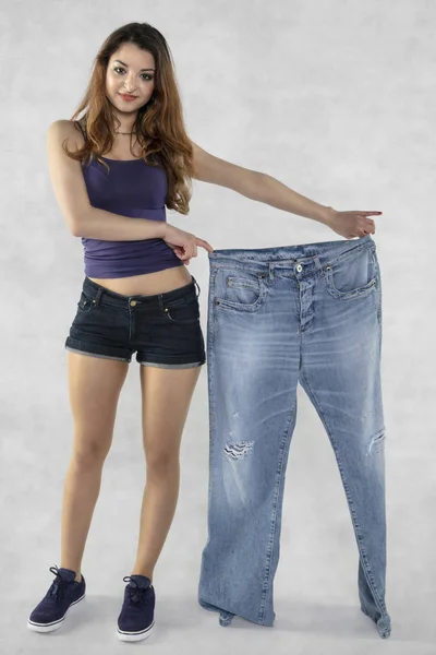 Молодая красивая спортивная девушка показывает, как сильно она похудела — стоковое фото