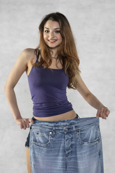 Young beautiful athletic girl shows how much weight she lost — Stock Photo, Image