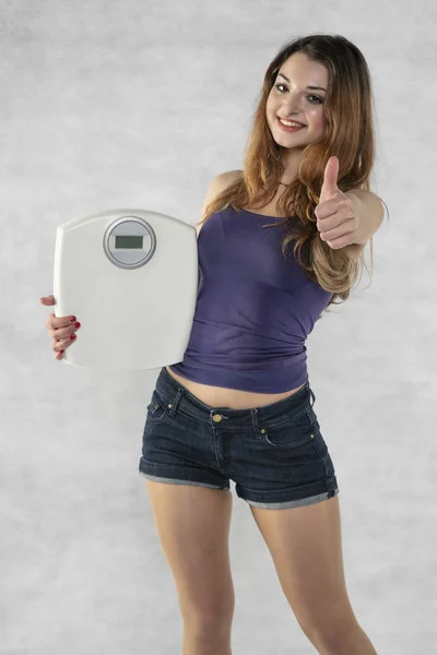 Young beautiful girl with a weight, weight loss symbol — Stock Photo, Image