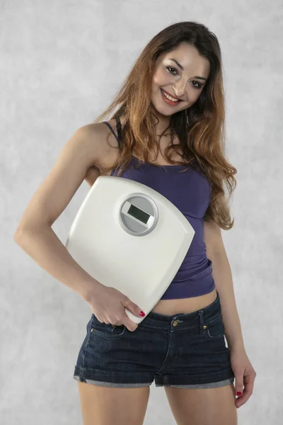 Young beautiful girl with a weight, weight loss symbol — Stock Photo, Image