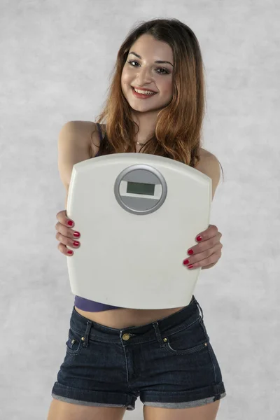 Young beautiful girl with a weight, weight loss symbol — Stock Photo, Image