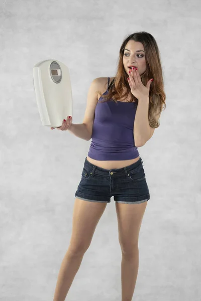 Young beautiful girl with a weight, weight loss symbol — Stock Photo, Image