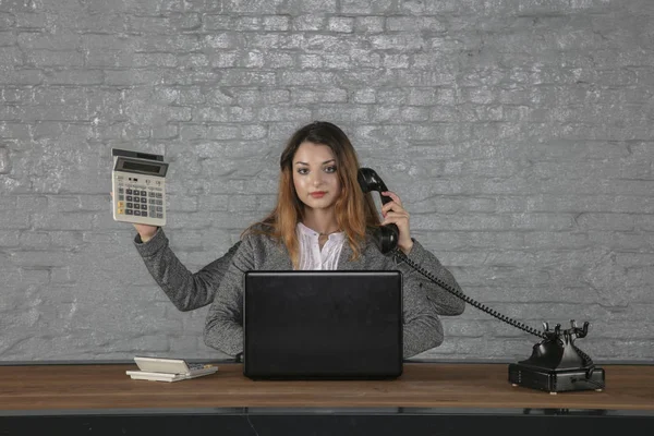 Giovane multitasking donna d'affari seduta alla scrivania — Foto Stock