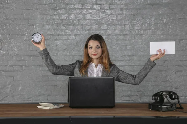 Een jonge zakenvrouw houdt een envelop en een horloge in haar hand — Stockfoto