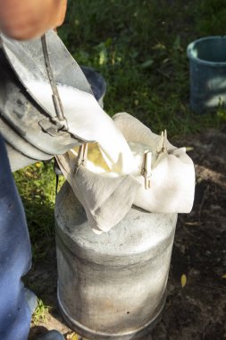 Çiftçi sütü süzgeçten geçirir, sütü çamurdan temizlemenin eski yolu.