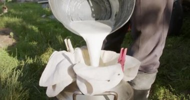  Bahçedeki çiftçi süzgeçten süt döker.
