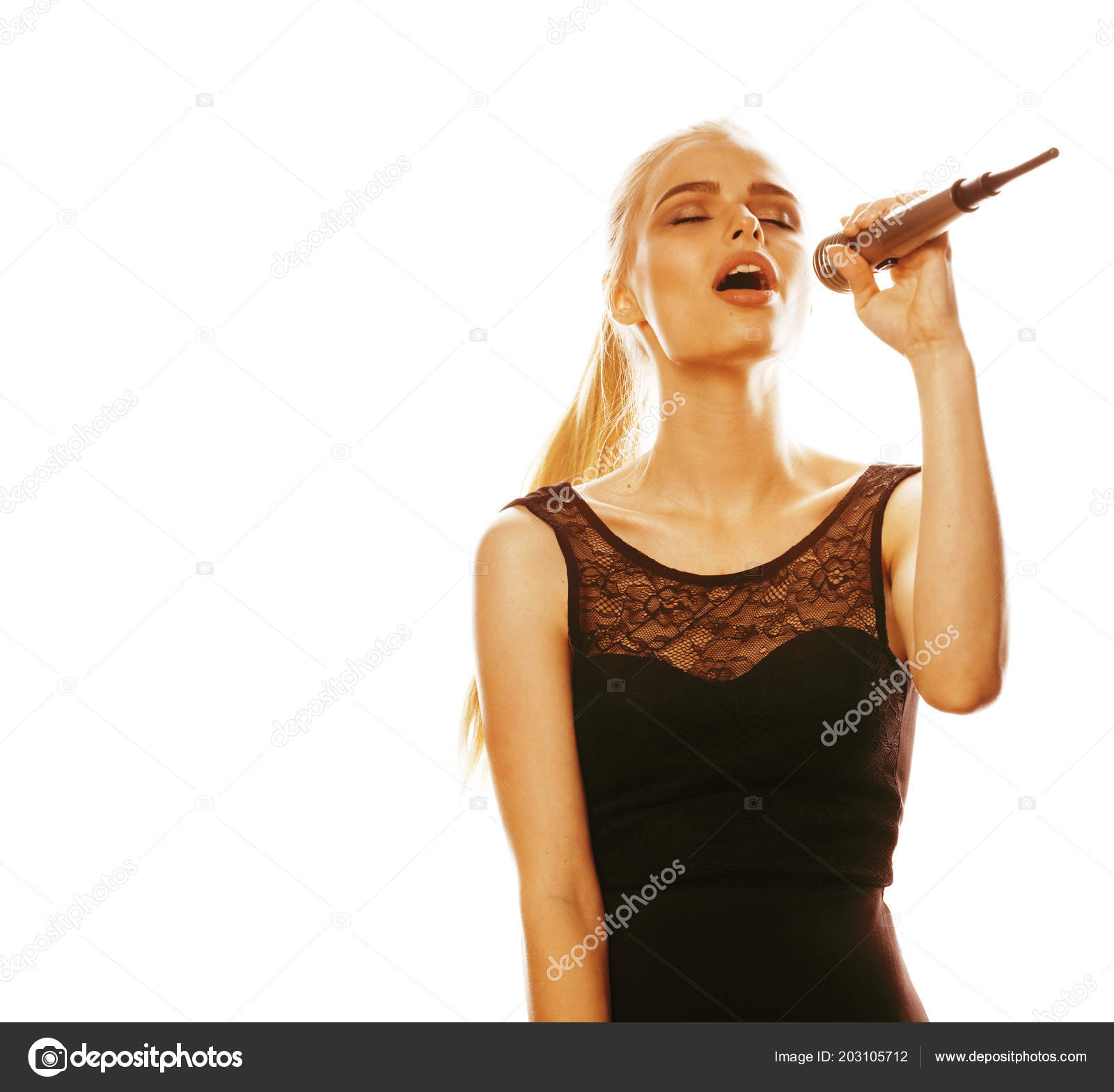 Молодая Красивая Блондинка, Поющая В Микрофоне Стоковое Фото.