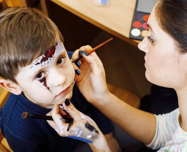 little cute child making facepaint on birthday party, zombie Apocalypse facepainting, halloween preparing concept, lifestyle people close up