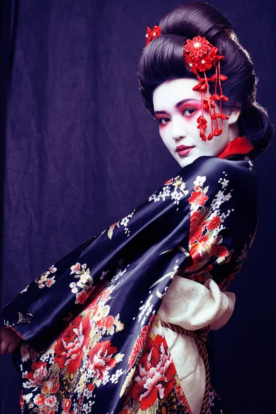 young pretty geisha in kimono with sakura and decoration on blac