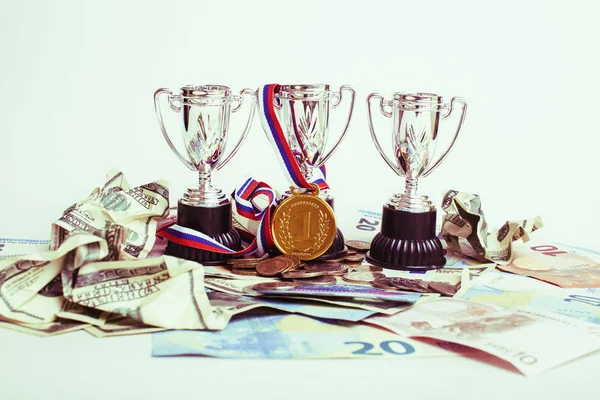 Sport winning concept: three cups among diverse currencies euro,